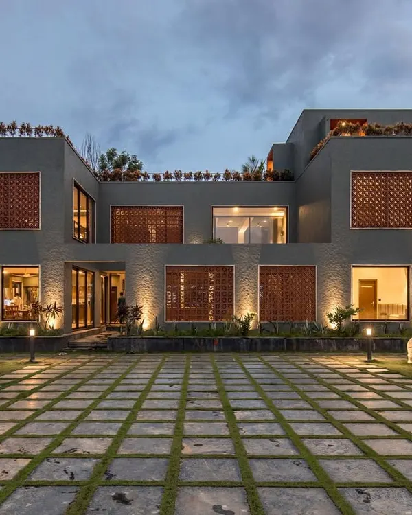 The Grey Grotto, our award-winning contemporary farmhouse, illuminated at dusk. This view showcases the home's strong geometric forms, integrated lighting, and the seamless blend of modern design with the natural landscape.