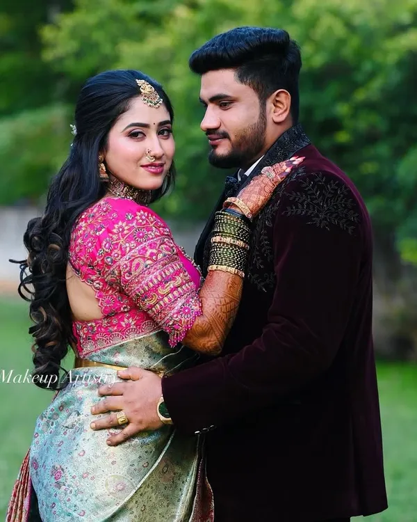 A romantic outdoor portrait of a couple. The bride's reception makeup features a soft glam look with defined eyes and a hairstyle of loose curls.