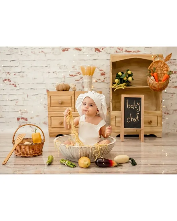 A little chef cooking up some fun. This baby is having a blast playing with spaghetti in our adorable miniature kitchen setup. It's a messy but memorable experience.