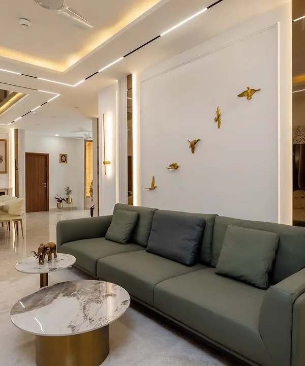 We designed this expansive living and dining area to be the heart of the home, perfect for both relaxation and entertaining. The design features a sophisticated palette of muted greens and whites, accented with gold details, marble flooring, and layered false ceiling lighting to create an atmosphere of modern luxury.