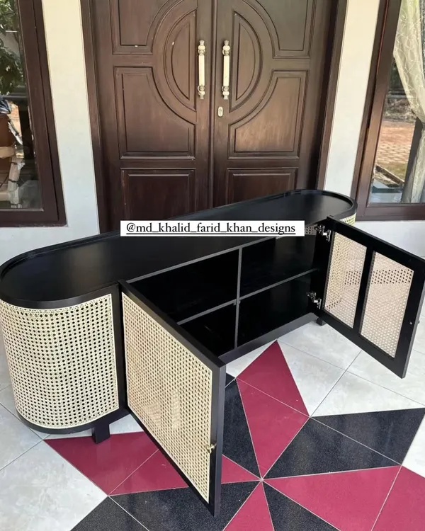 This custom-made sideboard features a unique oval shape with a black finish and cane-panelled doors. The doors are open to show the ample shelving inside, providing a stylish and practical storage solution for any entryway or dining room.