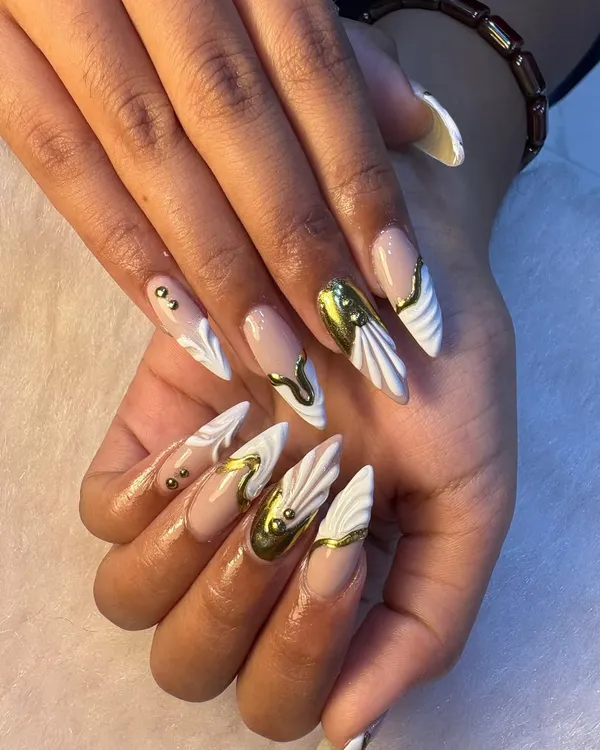We love creating statement nails like this set featuring sculpted white forms and bold, liquid gold chrome accents. This is the perfect example of how we combine different techniques like 3D art and chrome finish for a truly unique, luxury manicure.