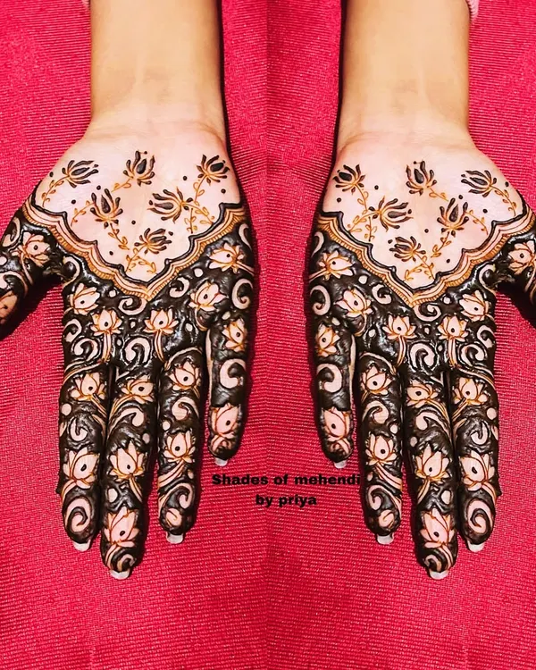 A beautiful, full-hand design with lotus motifs. The dark, bold work contrasts with the delicate buds on the back of the hand, creating a striking effect.