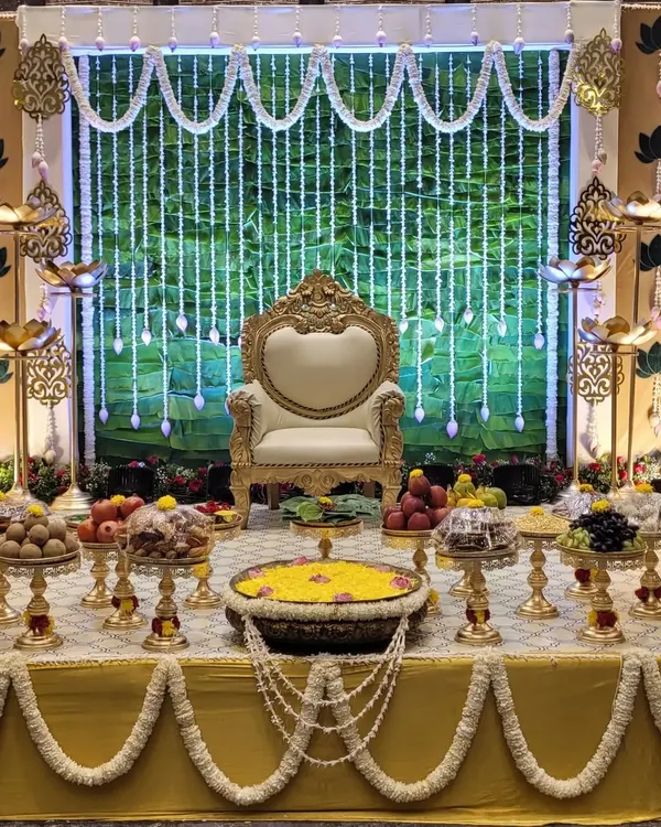 I designed this traditional baby shower stage with a lush green leaf wall and sparkling crystal hangings. The setup includes a royal chair for the mother-to-be and a fully arranged 'seer' table, creating a perfect blend of tradition and elegance for the Seemantha ceremony.