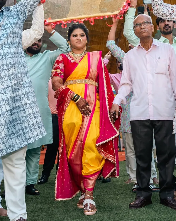 There's nothing like a perfectly draped Nauvari for a grand bridal entry. This bride is walking with confidence in a traditional yellow and pink dhoti-style drape, ready for her big moment.