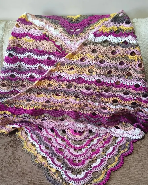 The finished Virus Shawl, draped to show its gorgeous, scalloped pattern. The self-striping yarn does all the colorwork for you, creating beautiful transitions from pinks and purples to yellows and greys.