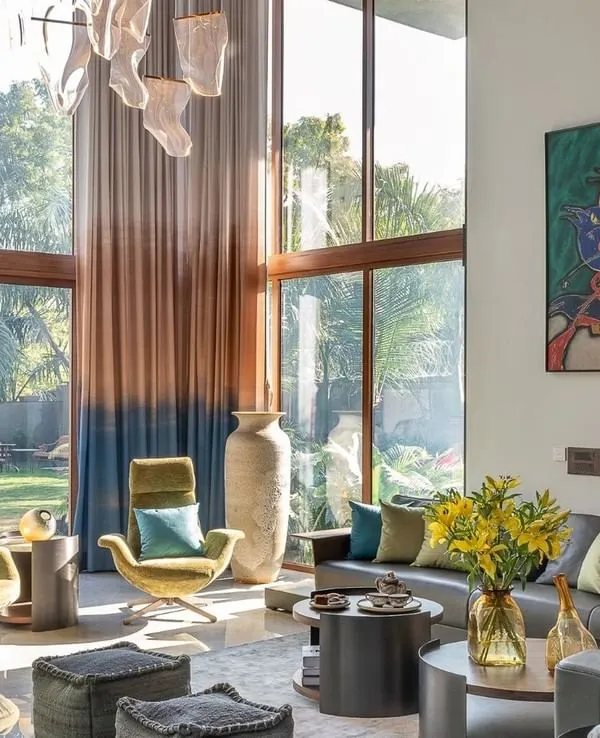 Sunlight floods this spacious living room through floor-to-ceiling windows, highlighting the vibrant artwork and designer furniture. We focused on creating a connection with the outdoors, making the room feel airy and expansive.