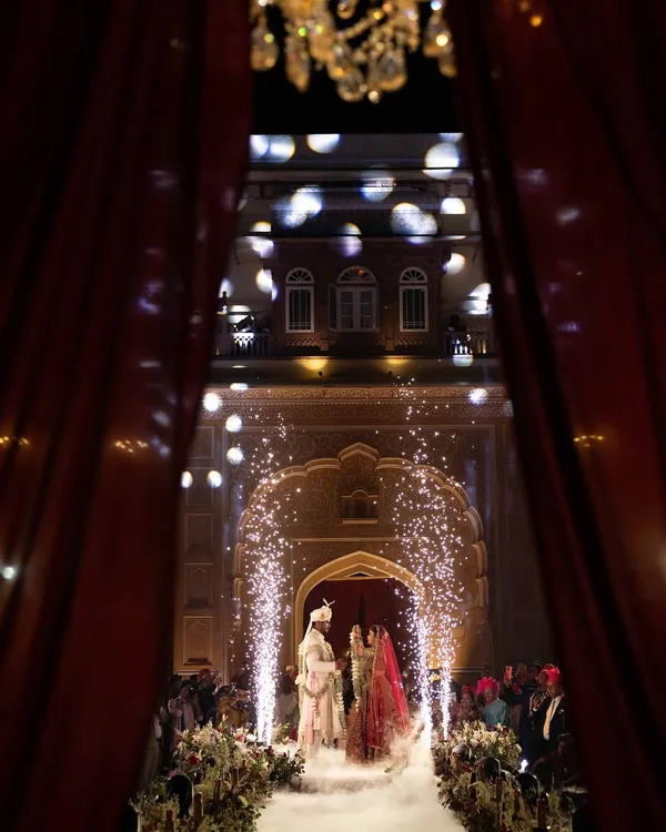 This is the moment that feels like a fairytale. I framed this couple's Varmala exchange with dramatic red curtains, a shower of petals, and sparkling pyrotechnics, creating an unforgettable, cinematic memory against the regal backdrop of Chomu Palace.