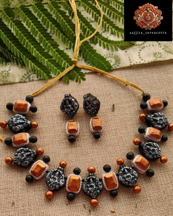 This artisanal necklace is a fusion of temple and stone jewelry styles. It features alternating Lakshmi charms and copper-colored stones, finished with black beads for a rustic, antique look.