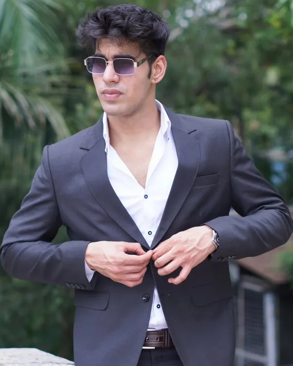 A classic charcoal grey blazer being buttoned up. This is a versatile piece for any man's wardrobe, perfect for a smart casual look.