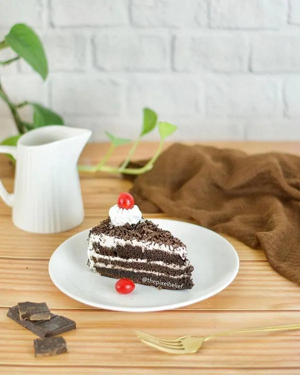 A clean and bright shot of a slice of black forest cake, styled simply for a cafe or bakery menu. This highlights the minimalist food photography style available.