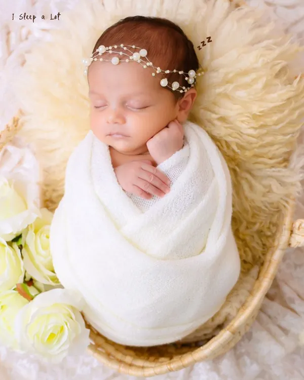 A classic portrait of newborn serenity. We gently swaddle your baby in a soft white wrap, creating a sense of security and peace that allows us to capture their perfect, sleeping form.