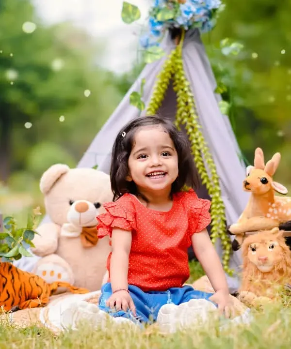 Anaya's second birthday shoot was a joyful outdoor picnic. The natural light and greenery create a beautiful setting, and the props make it extra fun.