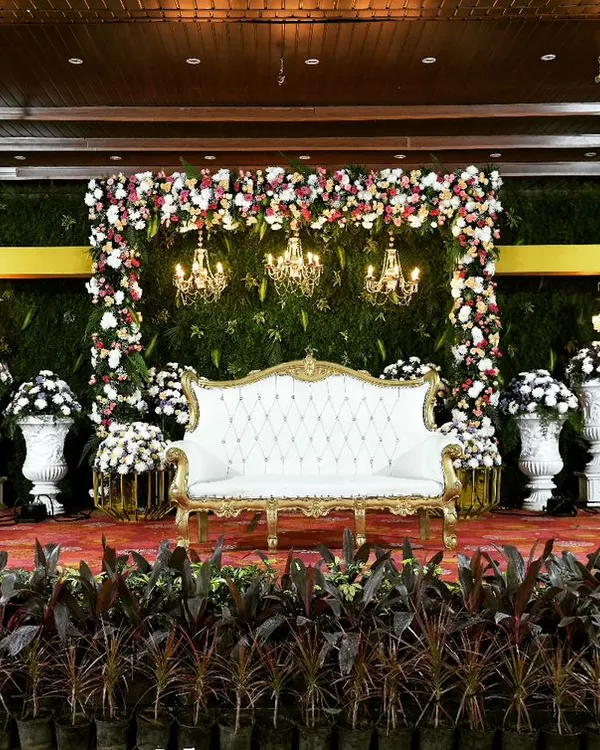 We designed this breathtaking reception stage with a nature theme, using a lush green backdrop, elegant floral arches, and classic chandeliers to create a romantic and sophisticated atmosphere for the happy couple.
