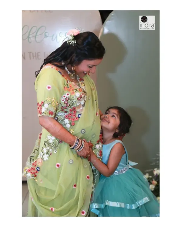 A beautiful, candid moment between a mother-to-be and her daughter, who is looking up at her mom and the baby bump with love and curiosity.