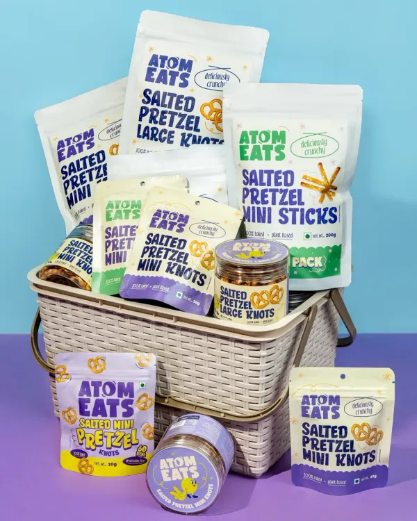 A basket overflowing with the full range of Atom Eats pretzel snacks. This shot effectively showcases the variety of packaging and product types, perfect for a website banner or promotional material.