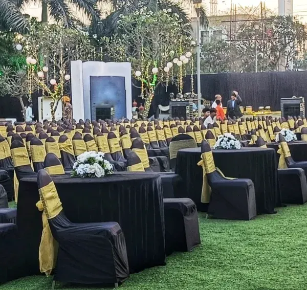 This outdoor venue features a mixed seating arrangement to serve different purposes. It includes banquet-style round tables for dining and rows of theater-style seating for a presentation or performance, all coordinated with a black and gold theme.