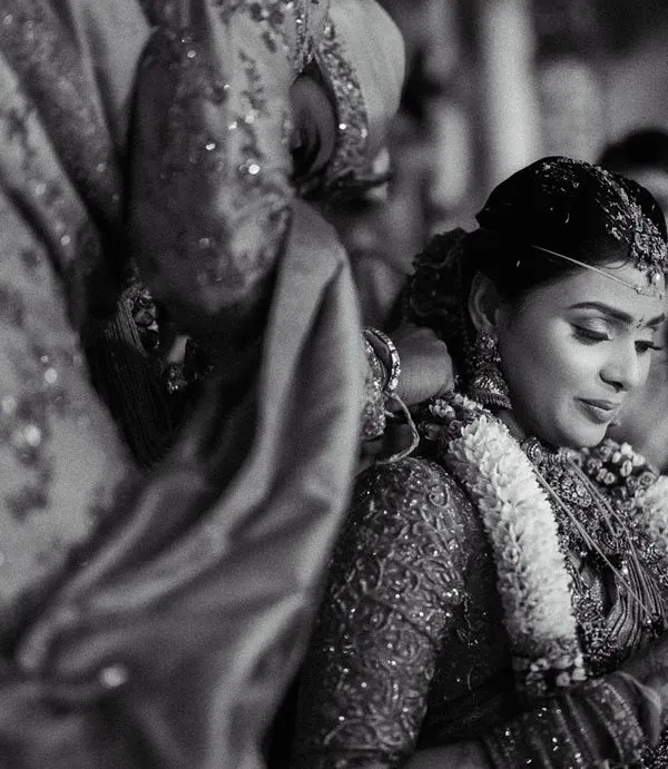 A close-up, black and white shot capturing the solemn moment of the mangalyam ceremony. This perspective emphasizes the significance of the ritual and the bride's serene expression.