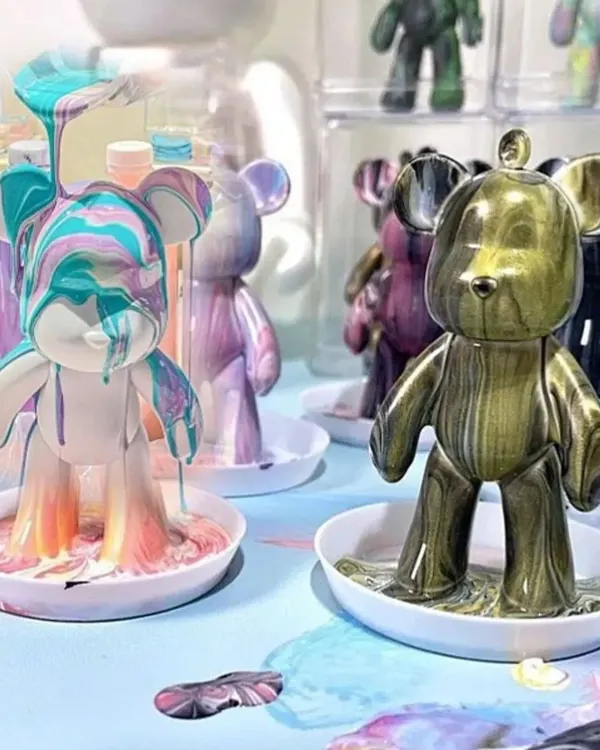 Watch the magic happen! This is the moment where you pour your custom-mixed colors over the bear and see your unique design come to life. I love guiding people through this super satisfying part of the fluid art process.