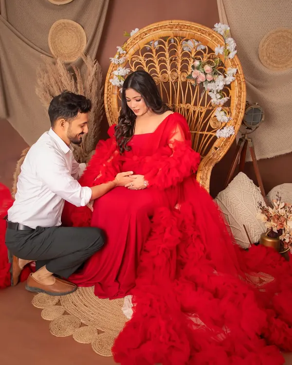 A tender moment between partners in our boho-themed studio setup. The vibrant red ruffled gown adds a touch of drama and romance, perfectly capturing the love and excitement of waiting for your little one.