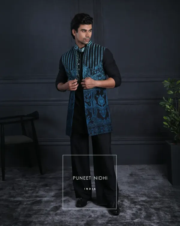 A tailored black Achkan paired with a teal embroidered jacket. The precise embroidery, bold contrast, and sharp mandarin neckline create a look of sophisticated, contemporary style.