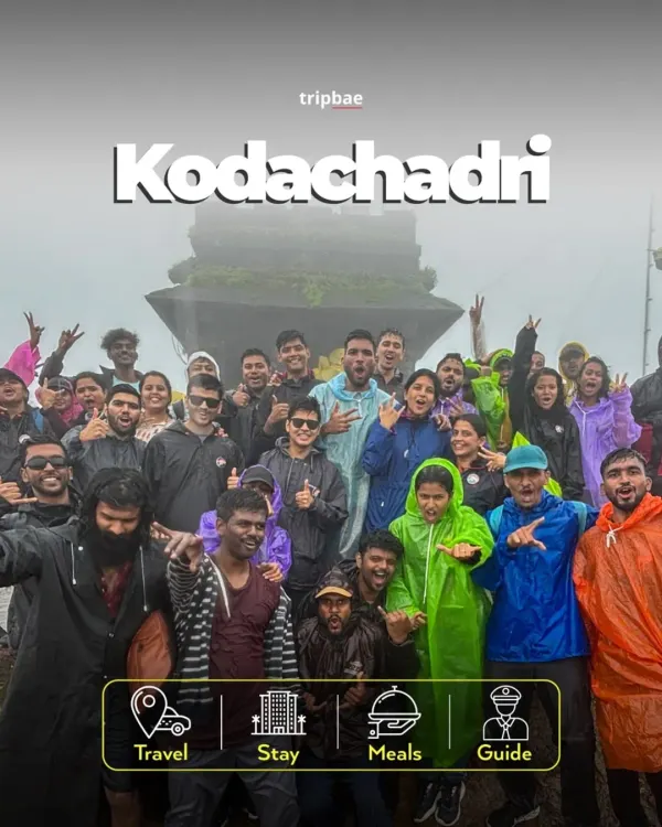 A large group celebrating at the top of Kodachadri, clad in raincoats. This trek is especially popular during the monsoon for its misty and magical atmosphere.