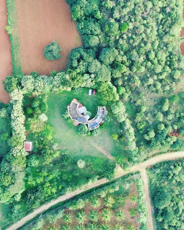An aerial drone shot of the 18-year-old farmhouse project in Nelamangala. This perspective truly shows how the structure is cradled by nature. The surrounding ring of trees, which I planned from the beginning, has now matured to provide a natural privacy screen and a habitat for local wildlife.