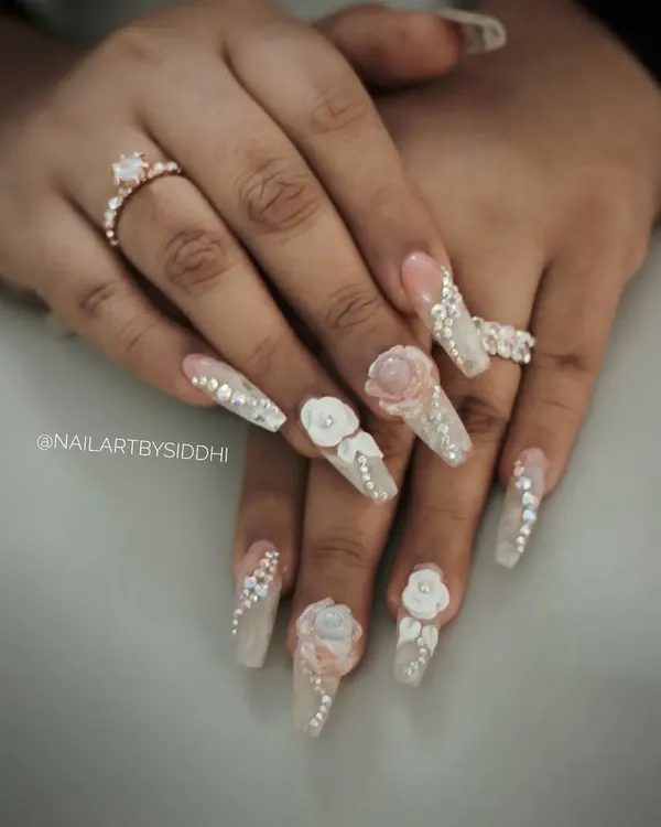 An exceptionally glamorous bridal set featuring long, coffin-shaped nails with 3D sculpted flowers, delicate pearl details, and a cascade of rhinestones. This is for the bride who wants to make a statement.