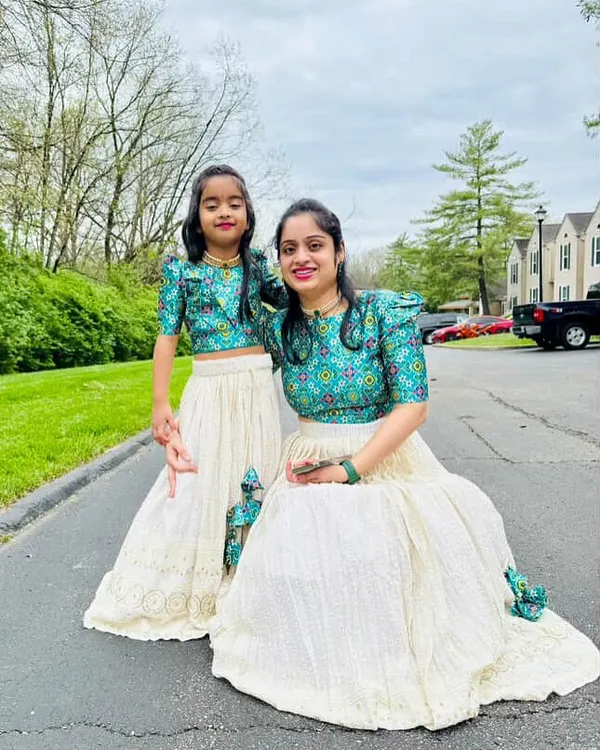 A mother and daughter duo looking lovely in their matching custom lehengas. This view shows how the coordinated teal printed blouses and cream chikankari skirts create a harmonious and stylish look.