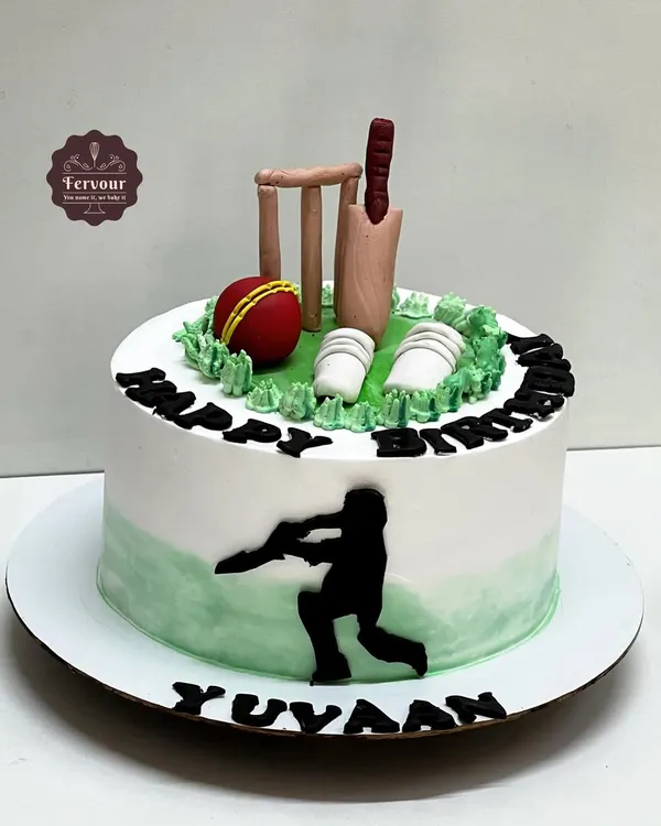 A classic cricket theme cake for a true fan. This design features a fondant bat, ball, and wickets on a field of green whipped cream, with a silhouette of a batsman on the side.