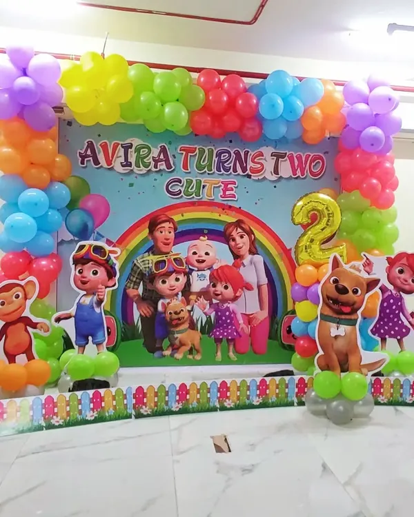 Here is a full-stage Cocomelon theme for a second birthday. The setup includes a large printed backdrop with all the characters, surrounded by a colorful balloon frame and standalone character cutouts for a complete and immersive party look.
