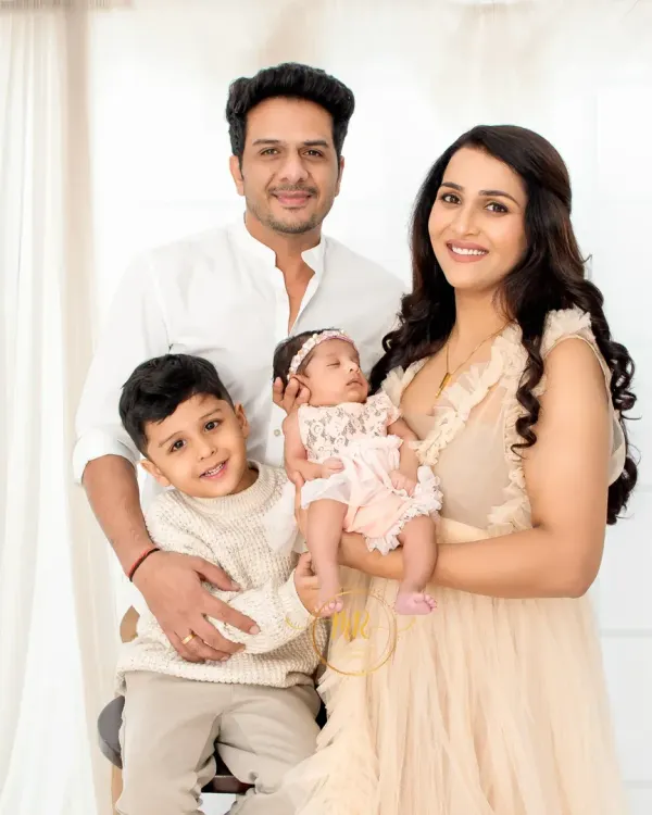 A beautiful family portrait of four. The parents and older brother look lovingly at the new baby girl, capturing a perfect family moment.