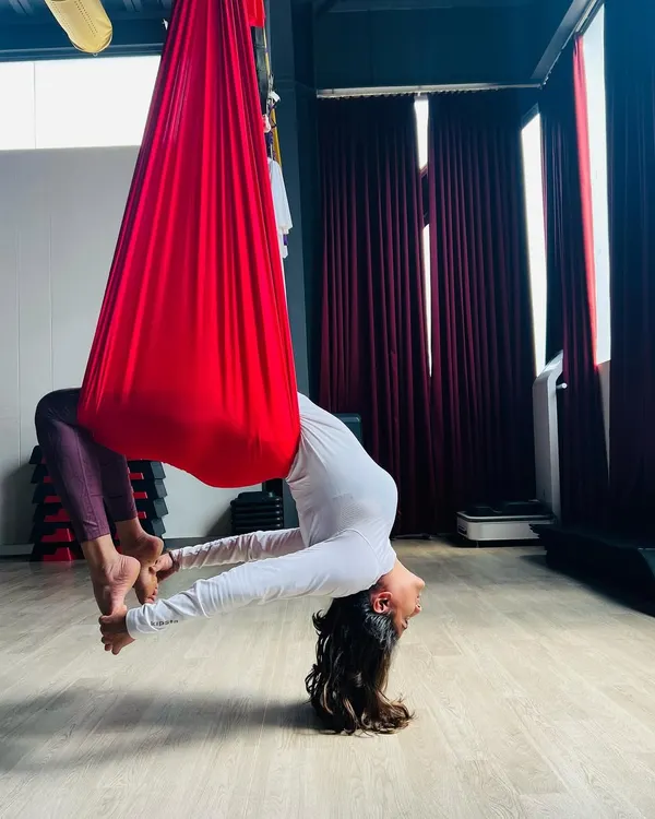 I believe life is better when you let go and allow yourself to evolve, one day at a time... This beautiful inversion, supported by the soft red hammock, is more than just a pose. It's a moment of trust and release that helps decompress the spine and open the heart. ❤️