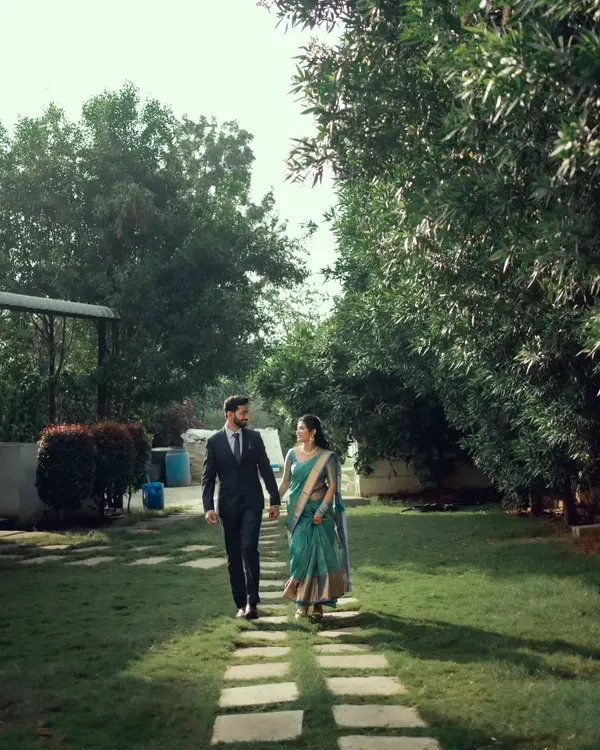 A candid moment of a couple walking hand-in-hand through a garden, lost in their own world.