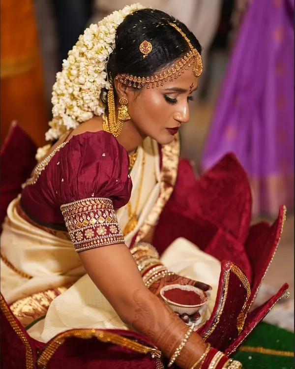A beautiful South Indian bride during her wedding rituals. We created a classic look with bold, defined eyes, a deep lip color, and a traditional floral hairstyle.