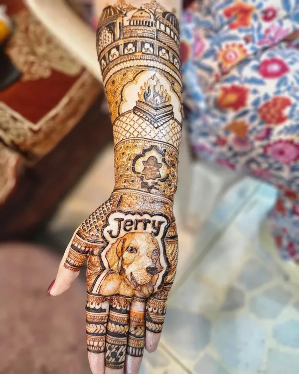 This bridal design tells a complete story. It features a portrait of the family dog 'Jerry' on the palm, a depiction of the wedding fire ceremony (havan kund), and the family temple on the arm.