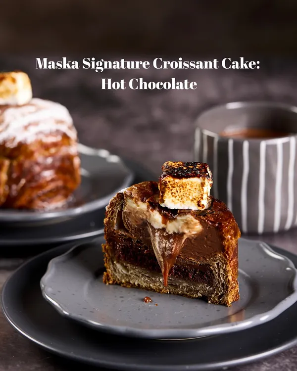 Our Signature Hot Chocolate Croissant Cake is pure indulgence. A buttery croissant holds a rich chocolate cake, salted caramel, and chocolate mousse, all topped with a torched marshmallow for that campfire hot chocolate feel.