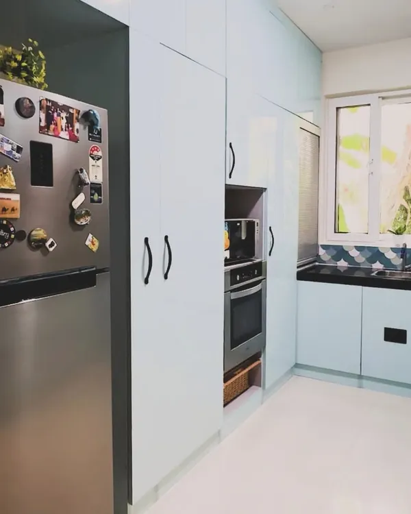 This U-shaped kitchen is brought to life with beautiful pastel blue cabinets. The design includes a tall unit with an integrated oven and microwave, showcasing how color can be combined with complete functionality.