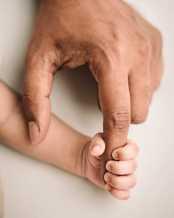 The tiniest hand wrapped around dad's finger. This iconic shot shows the immediate bond and the incredible smallness of your newborn.