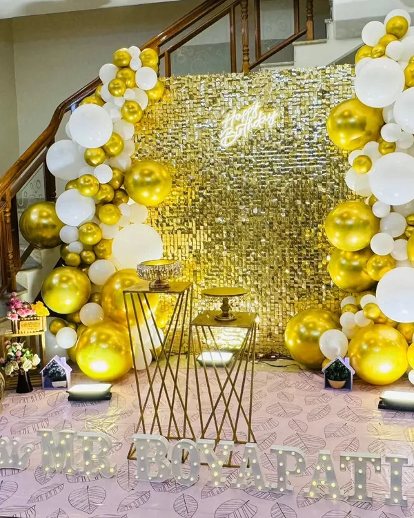 A glamorous gold and white theme featuring a full gold sequin backdrop, framed by a balloon arch.