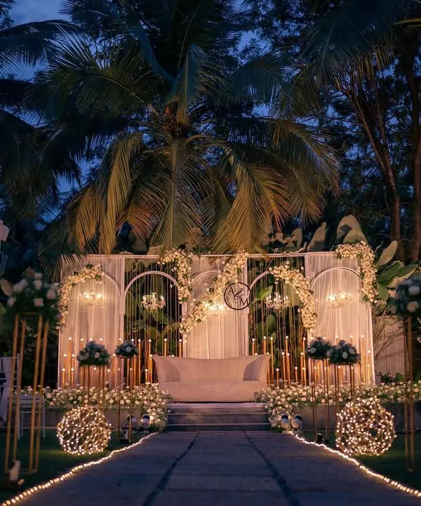This is the essence of a dream wedding reception. I designed this magical outdoor setting with a canopy of fairy lights, elegant white and gold stage decor, and an illuminated aisle to create a truly enchanting atmosphere for the couple and their guests.