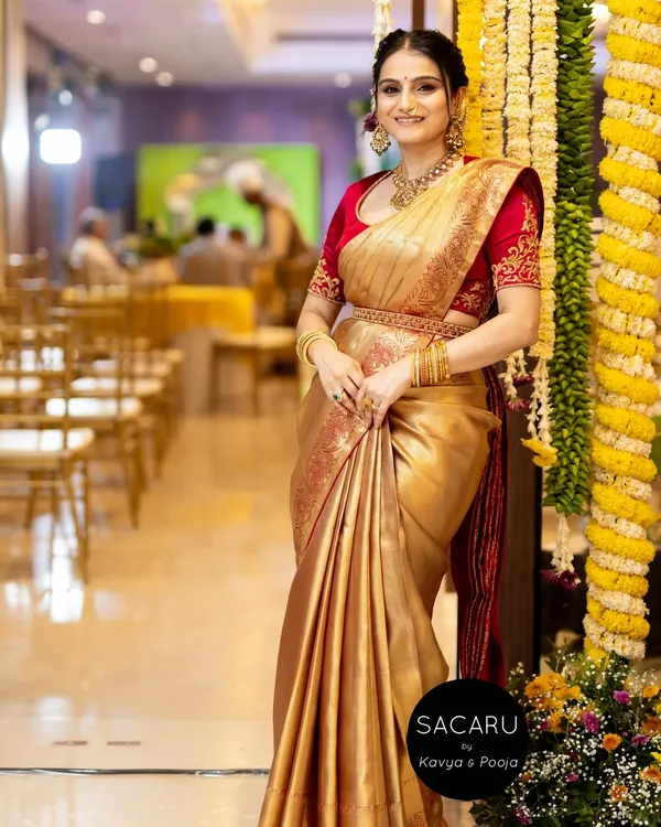 Our radiant client Anusha, celebrating a special family occasion in a custom cherry red satin blouse and a lustrous gold Kanjeevaram saree.