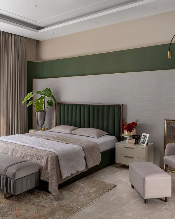 This calming bedroom features a deep green velvet headboard set against a multi-layered, textured wall. We use color with intent, creating a focal point that adds personality and depth without overwhelming the serene atmosphere.