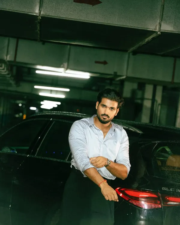 A moody, cinematic shot in an underground parking garage. The industrial setting and direct lighting create a gritty, urban feel, perfect for a modern menswear campaign.