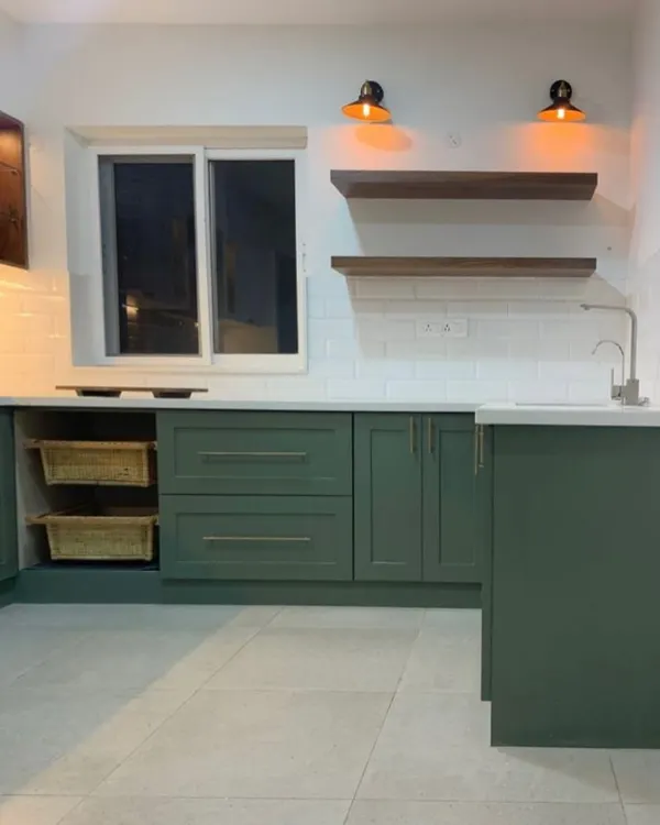 This kitchen doesn’t just cook—it judges your takeout habits and still makes you feel at home. A beautiful sage green kitchen with open shelving and warm lighting.
