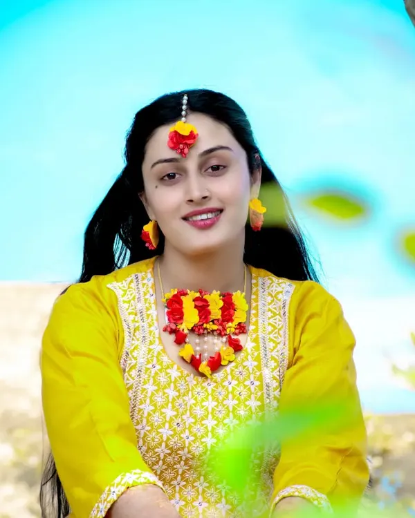 A beautiful portrait of the bride-to-be during her mehndi or haldi ceremony, adorned with floral jewelry. The bright yellow of her outfit is full of festive energy.