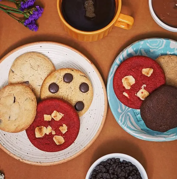 A top-down flat lay of assorted cookies, coffee, and chocolate, creating a warm and inviting scene. This style is effective for cafe menus, baking blogs, and social media content for food brands.