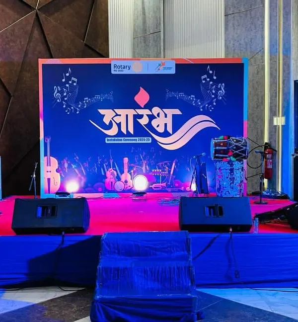 A full view of the stage we set up for the "Aarambh" event by Rotary Club Bhiwadi. The setup includes a branded backdrop, professional speakers, and stage monitors.