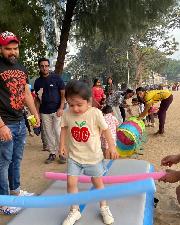 A toddler carefully navigates a balance challenge with help from our coaches and his dad. Our beach parties are designed for all ages, focusing on building confidence through play.