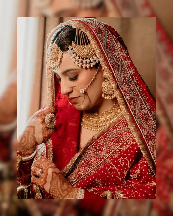 A stunning close-up of our Punjabi bride, Arsh. This portrait highlights her magnificent jewelry, the intricate details of her red bridal lehenga, and her serene expression on her wedding day.